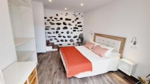 1 dormitorio con cama blanca y manta naranja en El Nido Agaete, en Agaete