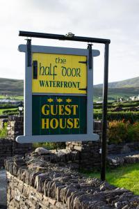 a sign for a guest house on a stone wall at Half Door House in Dingle