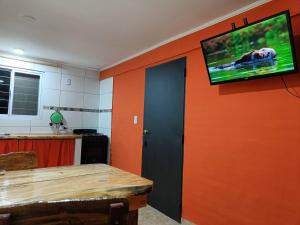 Habitación con pared de color naranja y TV en la pared. en Rayo Solar Depto Rama Caída en San Rafael