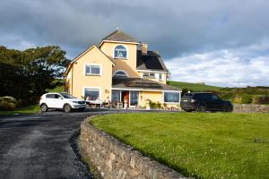 a house with two cars parked in front of it at Half Door House ROOM ONLY in Dingle