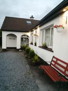a red bench sitting outside of a white building at Puffin rooms in Lisdoonvarna