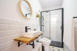 een badkamer met een wastafel, een toilet en een spiegel bij Villa Ria in Ovar