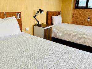 a hotel room with two beds and a lamp on a table at Quito Terrace in Quito