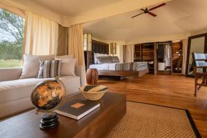 a living room with a couch and a bed at Aurari Camp in Serengeti