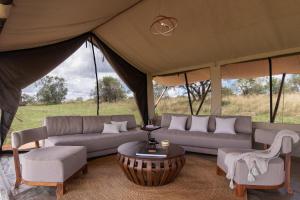 ein Wohnzimmer mit einem Sofa und Stühlen in einem Zelt in der Unterkunft Aurari Camp in Serengeti-Savanne