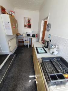 a kitchen with a sink and a stove top oven at SINGER HOUSE ,PAIGNTON SEAFRONT ,SLEEPS 6 , 2 BEDROOM GROUND FLOOR SELF CONTAINED GARDEN FLAT , PRIVATE ENTRANCE , KITCHEN , Guaranteed Parking ,Wifi , Movies ,Bathroom ,fridge , microwave ,BEDROOM 1, DOUBLE BED & 2 SINGLE BEDS ,BEDROOM 2 , DOUBLE BED in Paignton