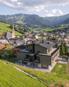 ein Gebäude auf einem Hügel mit einer Stadt im Hintergrund in der Unterkunft Bergleben Maria Alm - Haus Panorama in Maria Alm am Steinernen Meer