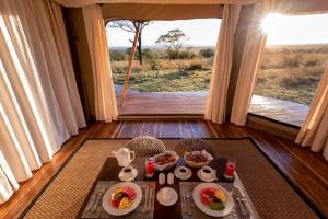 una mesa con comida en una habitación con vistas en Aurari Camp, en Serengeti