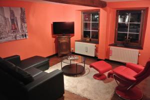 sala de estar con sofá negro y sillas rojas en La Doyenne, en Francorchamps