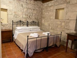1 dormitorio con 1 cama en una pared de piedra en Agriturismo Il Melograno, en Cannizzara