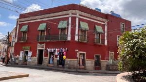 a red building on the side of a street at CAPITAL O Meson De La Fragua in Guanajuato