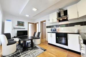 a kitchen with white cabinets and a table and chairs at Lora in Rakovica