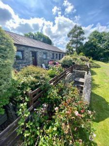 una casa con un giardino con fiori di fronte di Hafoty Farm Cottages a Caernarfon