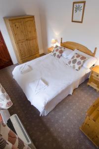 1 dormitorio con 1 cama blanca grande con almohadas en Hafoty Farm Cottages en Caernarfon