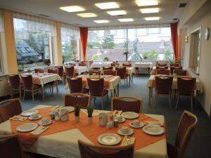 a dining room with tables and chairs and windows at Hotel Malchen garni GmbH in Seeheim-Jugenheim