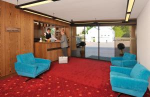 Hotel Malchen Garni في زيهايم يوغنهايم: رجل يقف في كونتر في غرفة مع كراسي زرقاء