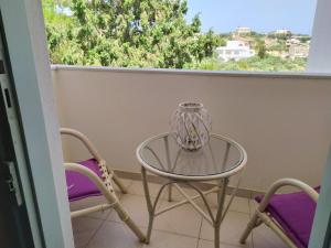 een glazen tafel en 2 stoelen op een balkon bij Agni apartment - Sunset in Blue in Ierápetra