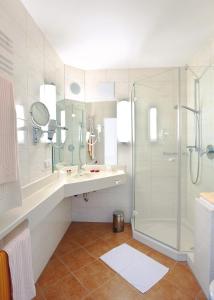 baño blanco con ducha y lavamanos en Hotel Malchen Garni en Seeheim-Jugenheim