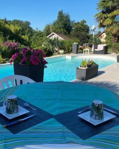 a table with a blue table cloth next to a swimming pool at Domaine de la Provençale in Saint-Didier-de-la-Tour
