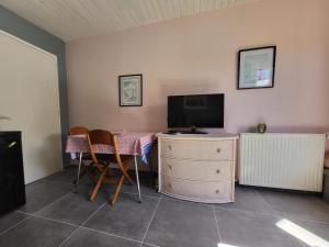 a room with a desk with a television and a table with chairs at Logement proche de Bordeaux, route des Châteaux in Ludon-Médoc