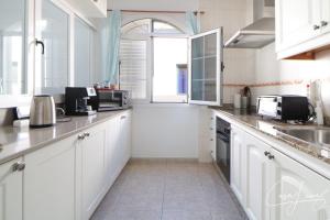 una cocina con armarios blancos y fregadero en Cliff View Orzola, en Orzola