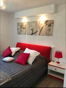 una camera da letto con un letto con cuscini rossi e bianchi di Appartement Veules roses , la cressonnière: « Veules & Victor «  a Veules-les-Roses