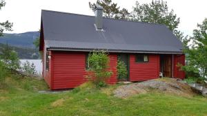 ein rotes Haus mit schwarzem Dach auf einem Hügel in der Unterkunft Teigen Leirstad, feriehus og hytter in Eikefjord