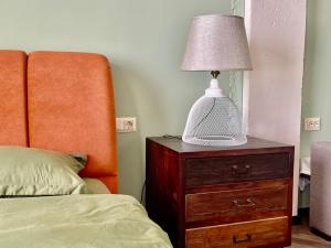 a lamp on a wooden dresser next to a bed at Claude Monet Seaside Hotel in Grigoleti