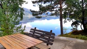 a wooden bench sitting in front of a lake at Teigen Leirstad, feriehus og hytter in Eikefjord