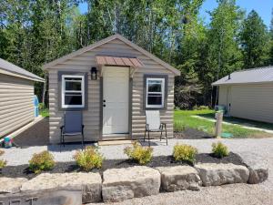 a small shed with two chairs in a yard at Adventure the Bruce Inn - Recently Renovated With Outdoor Hot Tub in Tobermory