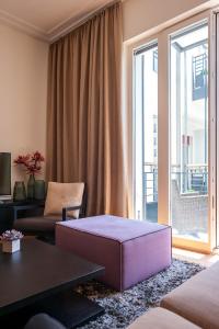 a living room with a purple ottoman in front of a window at The Wellem Residences in Düsseldorf
