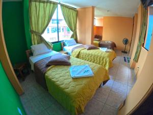 a hotel room with two beds and a window at Hostal Puyo in Puyo