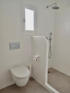 a white bathroom with a toilet and a window at ARK Tinos in Agios Ioannis Tinos