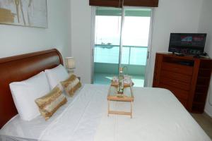 a bedroom with a white bed with a table on it at Ecusuites Salinas Resort 7F Departamento Piscina in Salinas