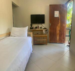 1 dormitorio con 1 cama, TV y escritorio en Recanto dos Irmãos en Itaúnas