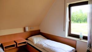 a small bed in a room with a window at Helles Ferienhaus im Landhausstil für bis zu 10 Personen in Frielendorf