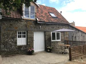 una casa in pietra con tavolo e ombrellone di Ferme de Noyes Cottage a Sourdeval