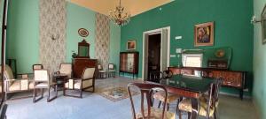una sala de estar con paredes verdes, mesas y sillas en B&B TOMMASO FAZELLO SCIACCA Residenza artistica en Sciacca