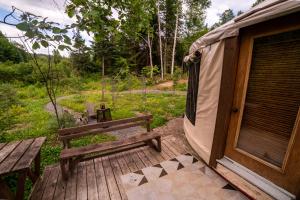 a tent and a bench on a wooden deck at La Lumineuse des yourtes du petit ruisseau in Mandeville