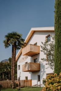 een wit gebouw met houten balkons en een palmboom bij La Loggia Georg in Pianizza di Sopra