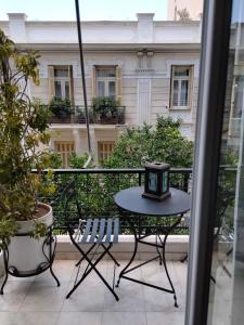 stół i krzesła na balkonie z zegarem w obiekcie AcropolisCozyStay w Atenach