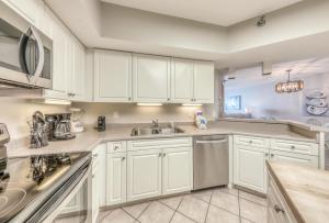 a kitchen with white cabinets and a sink at Bluewater in Orange Beach