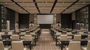 a lecture hall with tables and chairs and a screen at Pendry Park City in Park City