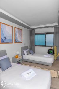two beds in a room with windows at Stayhere Agadir - Ocean View Residence in Agadir