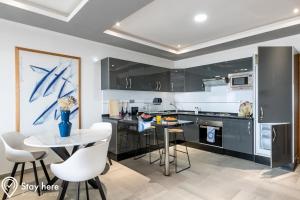 a kitchen with black cabinets and a table and chairs at Stayhere Agadir - Ocean View Residence in Agadir