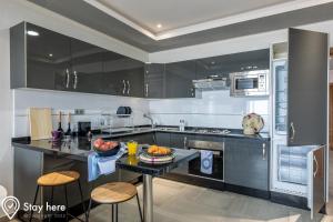 a kitchen with black cabinets and a table with food on it at Stayhere Agadir - Ocean View Residence in Agadir