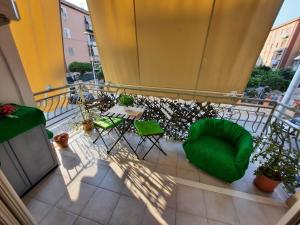 Un balcón con una silla verde y una mesa. en Campi Elisi, en Siracusa