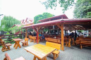 un patio avec des tables et des bancs en bois et un pavillon dans l'établissement Teju Hotels, à Slănic