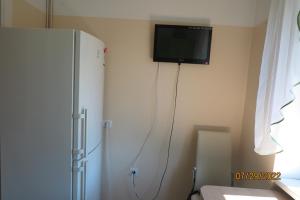 a tv on the corner of a room with a refrigerator at WILLOW apartamenti in Liepāja +2 photos