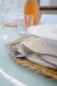 un tavolo bianco con piastra, forchetta e coltello di Villa Olea in Procida a Procida